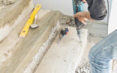 Partial focus of a man is working with reinforce concrete stair structure modification using hand drill machine in construction site